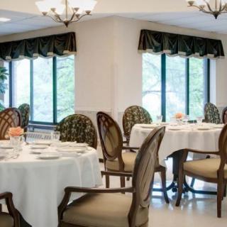 An elegant dining room with neatly arranged tables and chairs, featuring large windows.