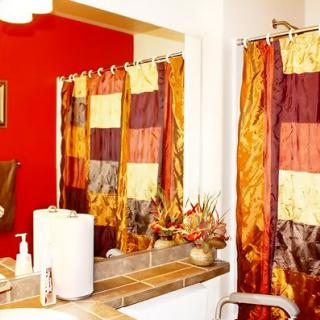 A brightly decorated bathroom with a red accent wall and colorful shower curtains.