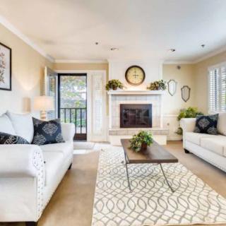 A modern living room with white sofas, a central fireplace, and a stylish coffee table.