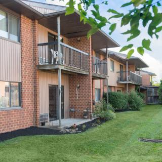 A row of brick apartment buildings with balconies and a well-maintained lawn.