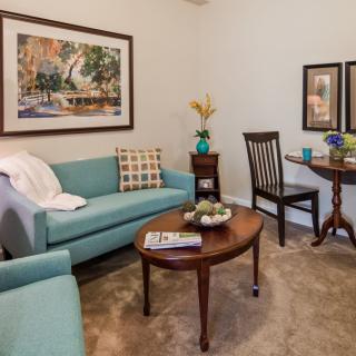 A cozy living room with a teal sofa, wooden coffee table, and decorative artwork on the walls.