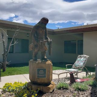 A statue standing in a garden area, accompanied by outdoor furniture.