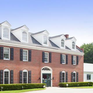 A large colonial-style brick house with multiple windows and dormers.