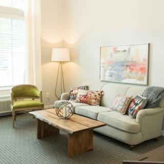 A cozy living room with a sofa, coffee table, and a stylish chair under natural light.