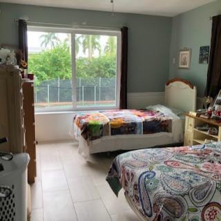 A cozy bedroom featuring natural light, colorful bedding, and a view of greenery outside.