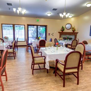 A cozy dining room with elegantly set tables and comfortable chairs, featuring a warm fireplace.