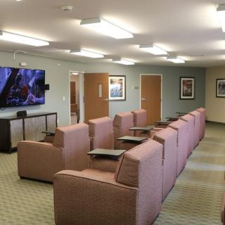 A comfortable lounge area with rows of cushioned chairs facing a large television.