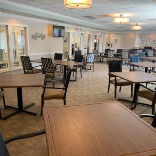 An empty dining area with neatly arranged tables and chairs, softly lit by overhead lights.