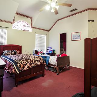A cozy bedroom with a bed, carpeted floor, and ceiling fan.