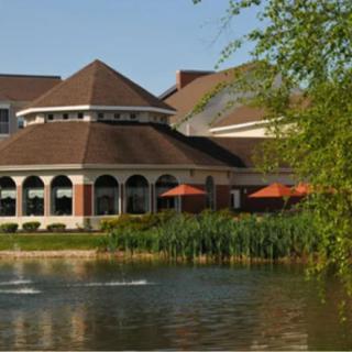 A scenic view of a building by a pond surrounded by trees.