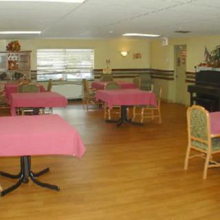 A dining area with pink tablecloths and wicker chairs on a wooden floor.