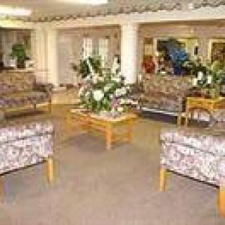 A cozy lobby area with patterned sofas, chairs, and a central table adorned with plants.