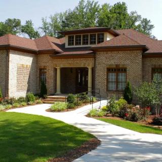 A beautiful brick house with well-maintained landscaping and a lush green lawn.