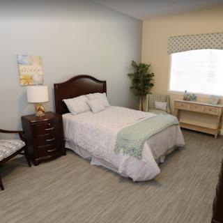 A cozy and modern bedroom featuring a single bed, nightstand, and a workspace by the window.