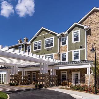 A modern residential building with a covered entrance and landscaped surroundings.