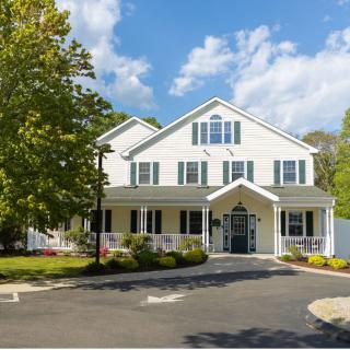 A two-story suburban house with a well-maintained yard and clear blue sky.