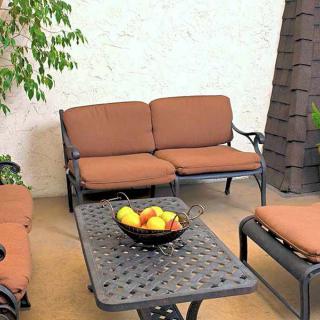 A cozy patio setup with brown cushioned seating and a table featuring a fruit bowl centerpiece.