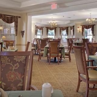 An elegant dining room with tables and chairs arranged under chandeliers.