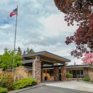 A building entrance with an American flag in the foreground surrounded by trees.