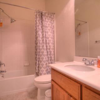 A cozy bathroom with a shower curtain, toilet, sink, and mirror.