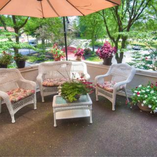 A cozy outdoor patio with wicker furniture and vibrant flowers.
