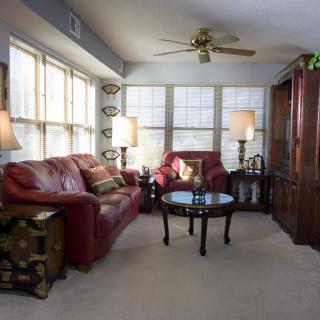 A cozy living room with red sofas, a coffee table, and large windows allowing natural light to fill the space.