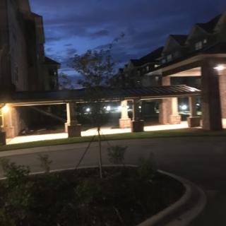 A well-lit parking area beside a building, captured during twilight.