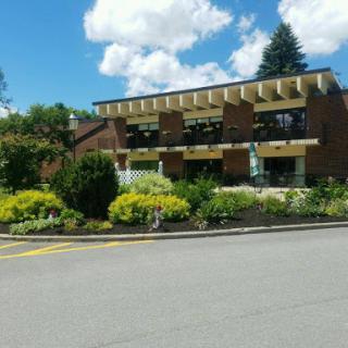 A beautifully landscaped building under a blue sky with fluffy clouds.