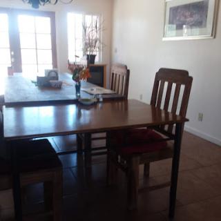 A cozy dining area featuring a wooden table and chairs, illuminated by natural light.