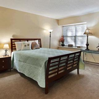 A cozy bedroom with a neatly made bed, two lamps, and a window providing natural light.