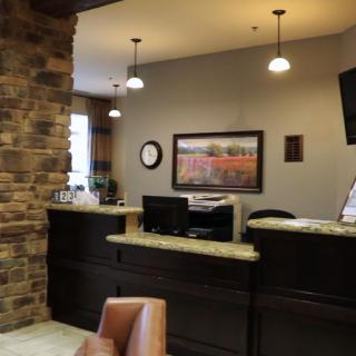 A well-lit reception area featuring a desk with a computer, decorative lighting, and a wall adorned with art.