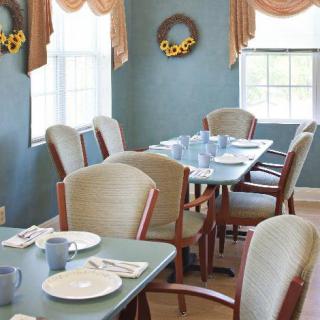 A neatly arranged dining room with table settings and decorative wreaths on the walls.