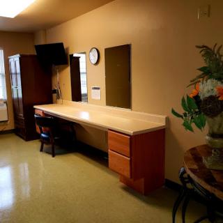 A simple and organized interior space featuring a desk, mirror, and some decorative elements.