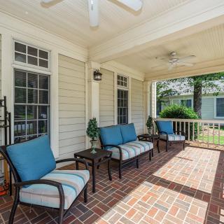 A cozy covered porch with comfortable seating and a brick floor, perfect for relaxing outdoors.