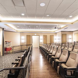 An empty auditorium with rows of comfortable seating and bright lighting.