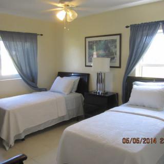 A cozy bedroom with two single beds, featuring blue curtains and a bedside lamp.