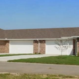 A suburban duplex with a driveway and well-maintained lawn.