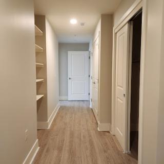 A spacious and well-lit hallway featuring shelves and multiple doors.