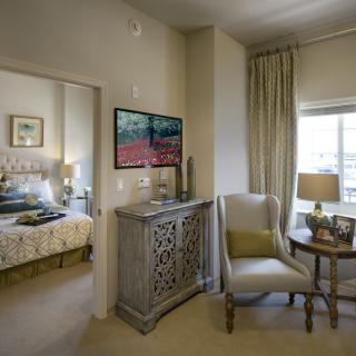 A cozy living space featuring elegant furniture and decor, with a view into a stylishly decorated bedroom.