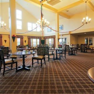 An elegant dining area with high ceilings, chandeliers, and neatly arranged tables and chairs.