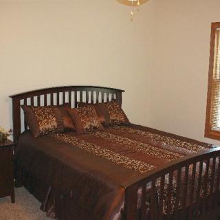 A cozy bedroom with a wooden bed frame and patterned bedding.