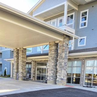 The modern building entrance features prominent stone pillars and large glass windows.