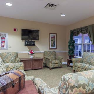A cozy living room with patterned furniture and a wall-mounted television.