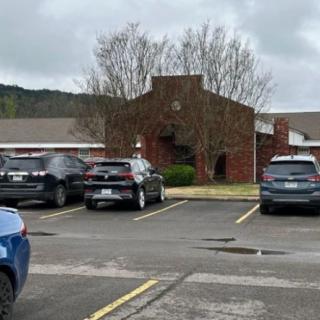 A parking lot in front of a brick building on a cloudy day.