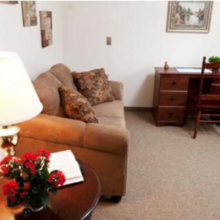 A cozy living room with a sofa, desk, and lamp.