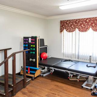 A small gym room with exercise equipment, including a set of dumbbells and a bench.