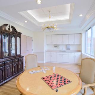 A bright and elegantly designed dining room featuring a round table, plush chairs, and a stylish wooden cabinet.