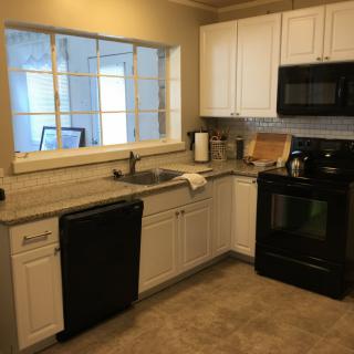 A modern kitchen with white cabinets and black appliances.