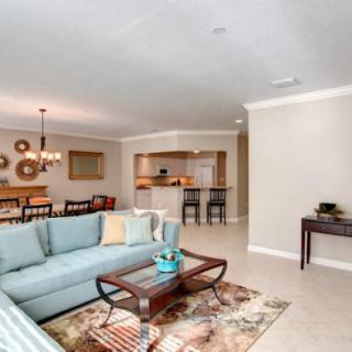 A modern open-concept living and dining area featuring a light blue sofa, wooden coffee table, and elegant dining set under a chandelier.