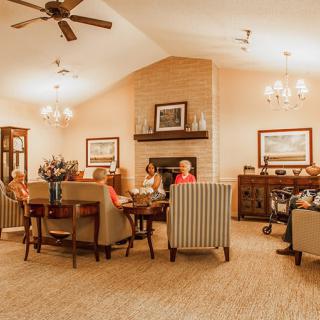 A cozy living room interior with a fireplace and people gathered around.
